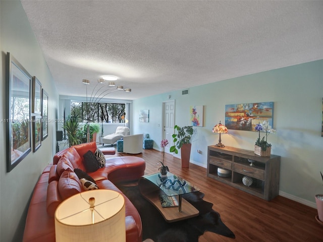 living room with visible vents, baseboards, a textured ceiling, and wood finished floors