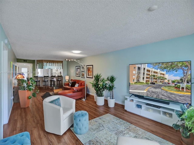 living area featuring a textured ceiling, baseboards, and wood finished floors