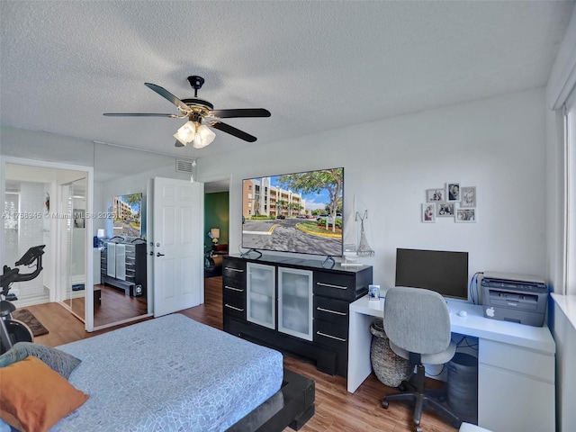 bedroom with visible vents, a textured ceiling, a ceiling fan, and wood finished floors