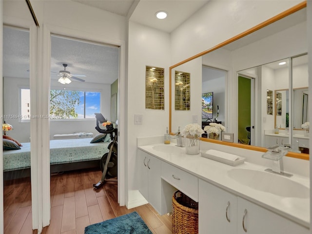 ensuite bathroom featuring a sink, connected bathroom, and wood finished floors