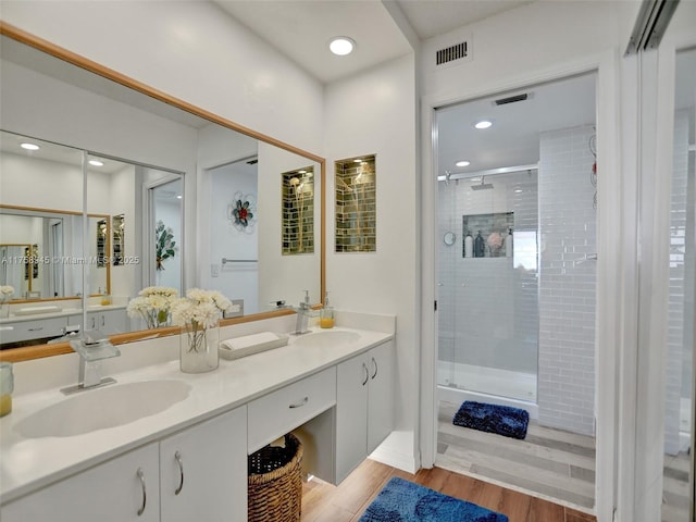 full bathroom featuring visible vents, a shower stall, wood finished floors, and a sink