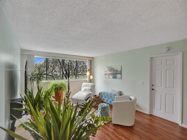 living area with wood finished floors, baseboards, and a textured ceiling