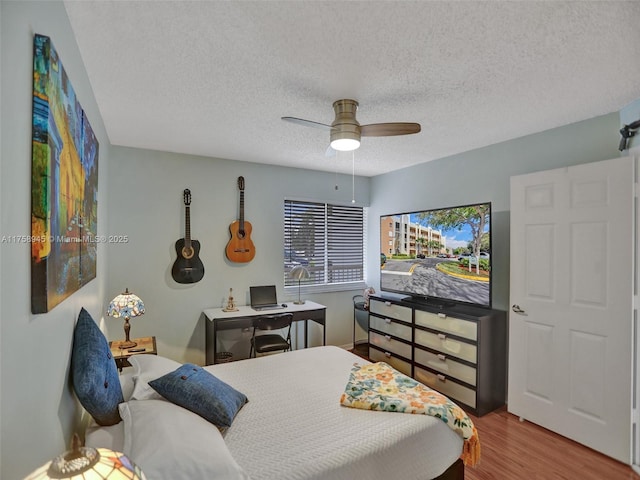 bedroom featuring a textured ceiling, wood finished floors, and a ceiling fan