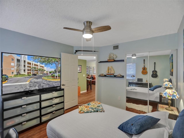 bedroom featuring visible vents, wood finished floors, a closet, a textured ceiling, and a ceiling fan