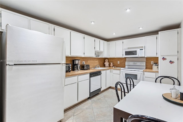 kitchen featuring light tile patterned floors, light countertops, backsplash, a sink, and white appliances