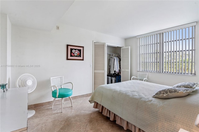 tiled bedroom featuring baseboards and a closet