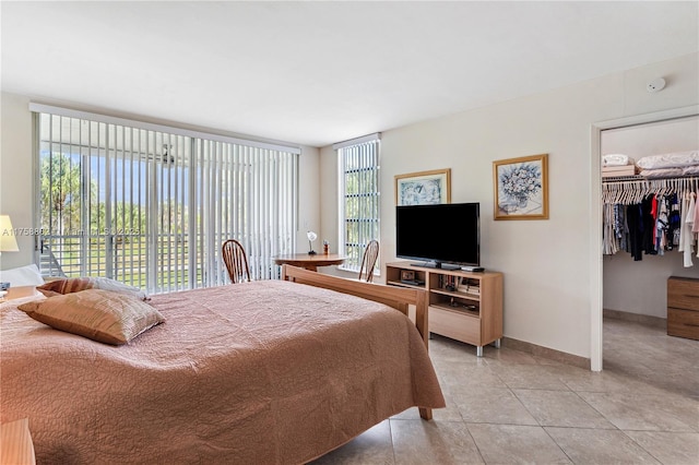 bedroom featuring light tile patterned floors, baseboards, a walk in closet, and a closet
