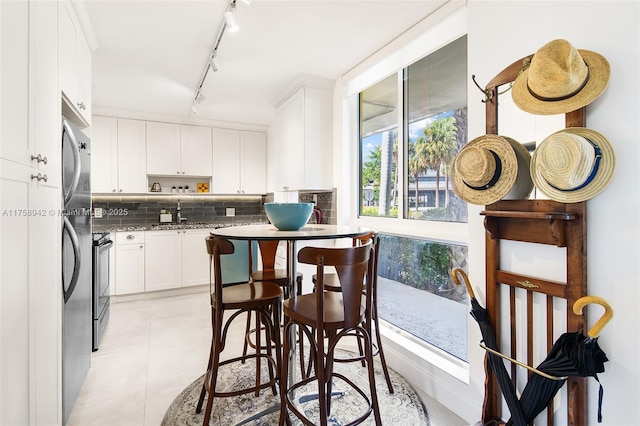 kitchen featuring light tile patterned flooring, white cabinetry, electric stove, tasteful backsplash, and rail lighting