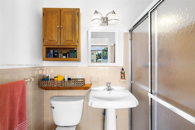 full bathroom with tile walls, a wainscoted wall, a shower stall, and toilet