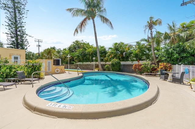 community pool with a fenced backyard and a patio