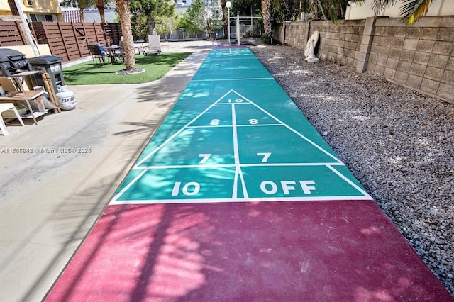 view of property's community featuring fence and shuffleboard