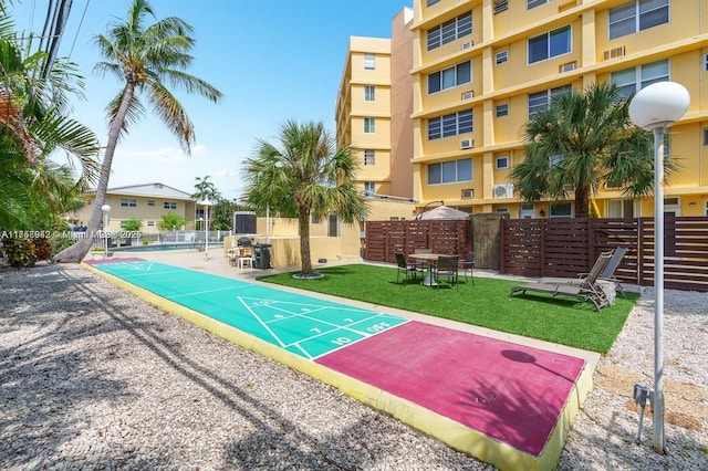 surrounding community with shuffleboard, a yard, and fence