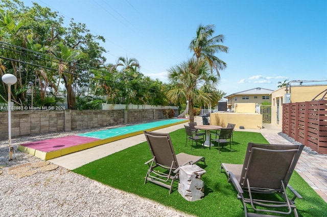 view of yard featuring fence and shuffleboard