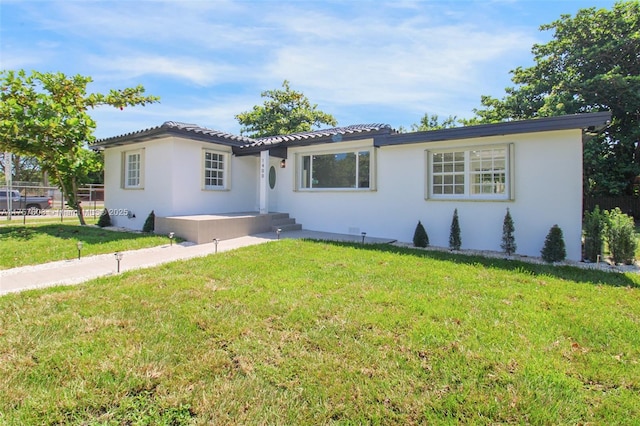 ranch-style home featuring stucco siding, fence, and a front yard