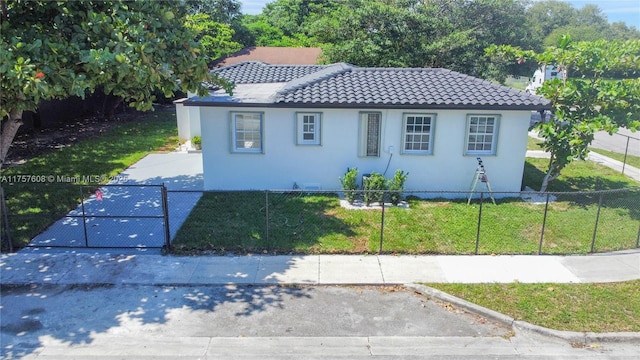 view of front of property featuring a tiled roof, a front lawn, a fenced front yard, and stucco siding