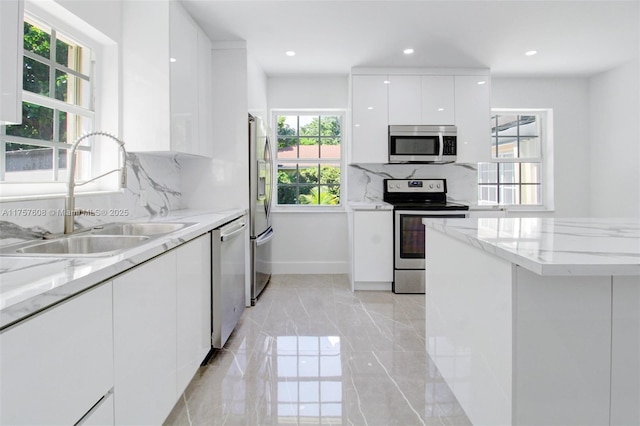 kitchen with marble finish floor, stainless steel appliances, white cabinets, a sink, and modern cabinets