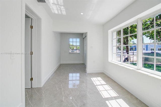 empty room featuring marble finish floor and baseboards