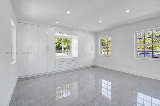 spare room with a healthy amount of sunlight, marble finish floor, and recessed lighting