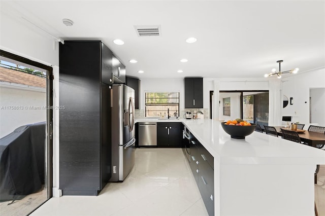 kitchen with light countertops, visible vents, appliances with stainless steel finishes, dark cabinets, and a peninsula