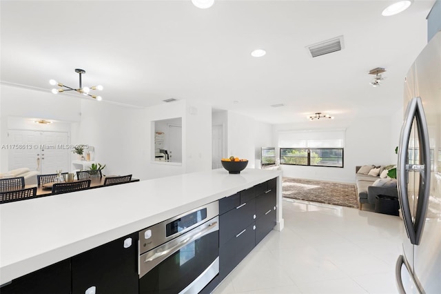 kitchen featuring appliances with stainless steel finishes, open floor plan, dark cabinetry, and light countertops