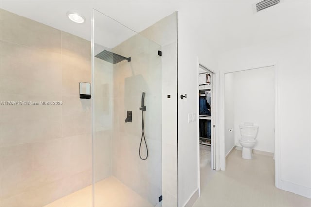 bathroom featuring a stall shower, baseboards, visible vents, toilet, and a walk in closet