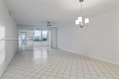 unfurnished room with light tile patterned flooring and an inviting chandelier