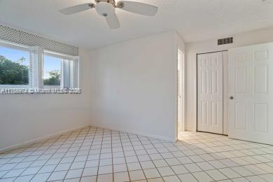 empty room with light tile patterned floors, ceiling fan, visible vents, and baseboards