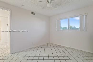 empty room featuring light tile patterned floors, ceiling fan, visible vents, and a textured ceiling