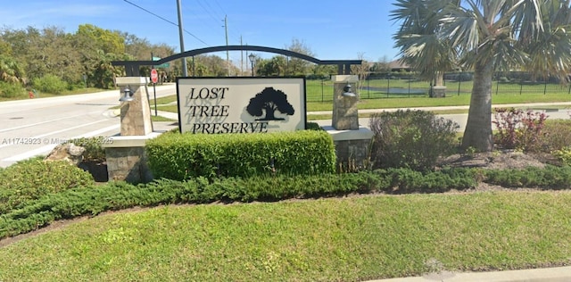 community / neighborhood sign featuring a yard and fence