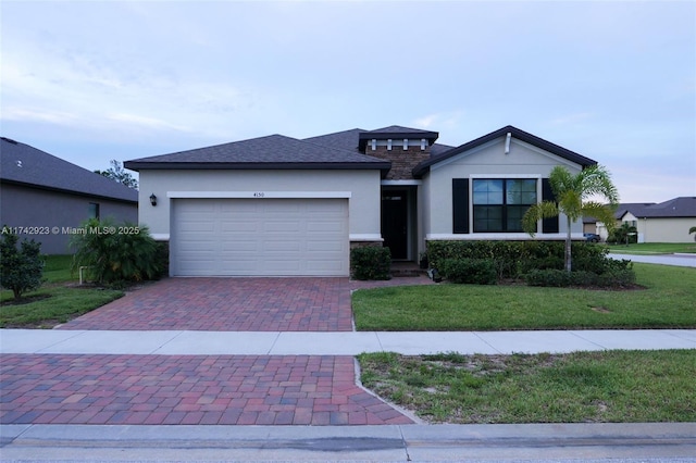 view of front of property featuring decorative driveway, a garage, a front lawn, and stucco siding