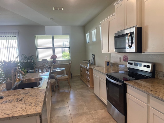 kitchen featuring visible vents, a sink, white cabinetry, stainless steel appliances, and light tile patterned floors