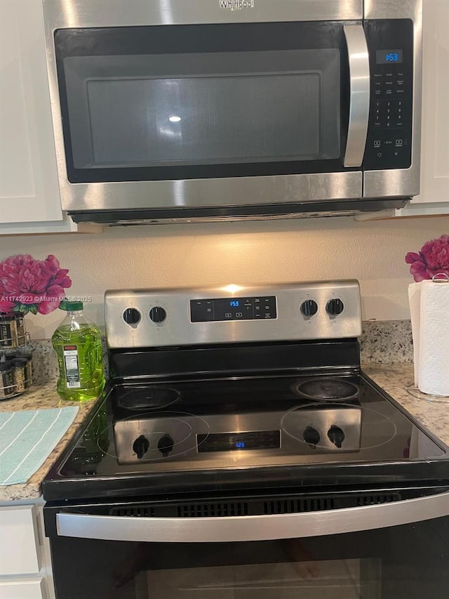 interior details featuring stainless steel microwave, white cabinets, light countertops, and range with electric stovetop