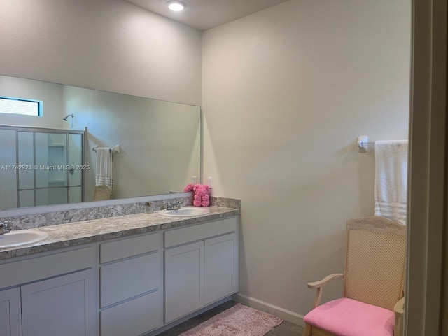 bathroom featuring double vanity, baseboards, a stall shower, and a sink