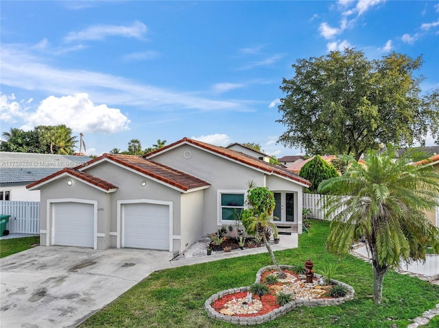 mediterranean / spanish-style home featuring a garage, fence, concrete driveway, stucco siding, and a front yard