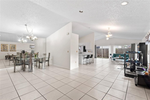 dining space featuring light tile patterned floors, vaulted ceiling, a textured ceiling, and ceiling fan with notable chandelier