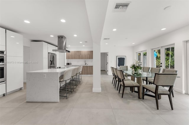 kitchen with visible vents, modern cabinets, island exhaust hood, a kitchen island, and appliances with stainless steel finishes