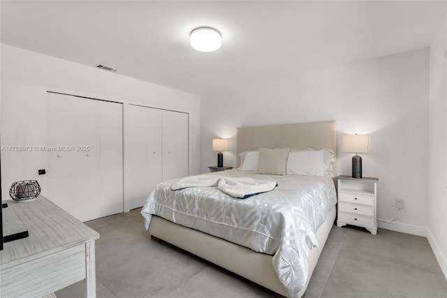 bedroom featuring visible vents, multiple closets, concrete flooring, and baseboards