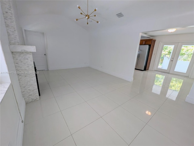 spare room featuring french doors, visible vents, vaulted ceiling, and light tile patterned flooring