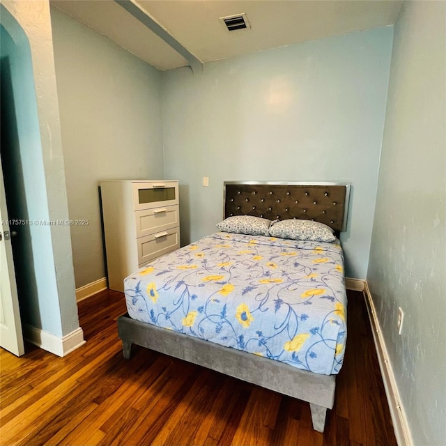 bedroom featuring arched walkways, wood finished floors, visible vents, and baseboards