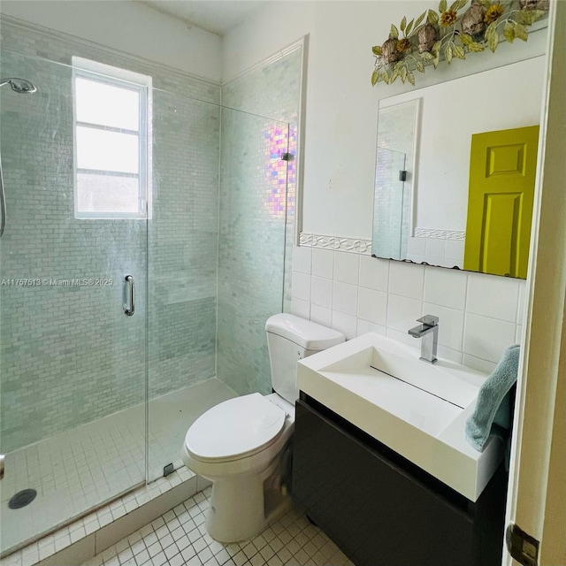 bathroom featuring tile walls, toilet, a stall shower, vanity, and tile patterned floors