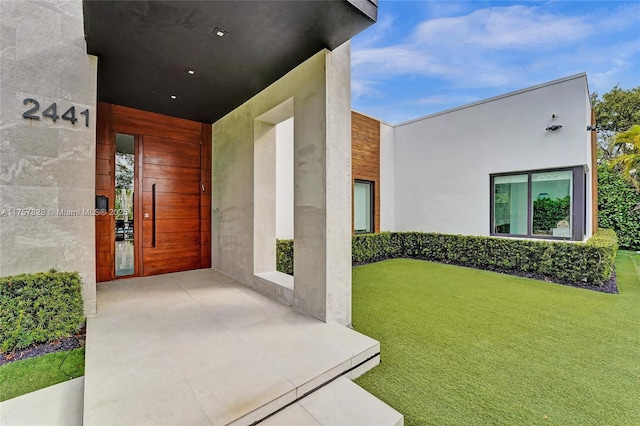 doorway to property with a yard and stucco siding