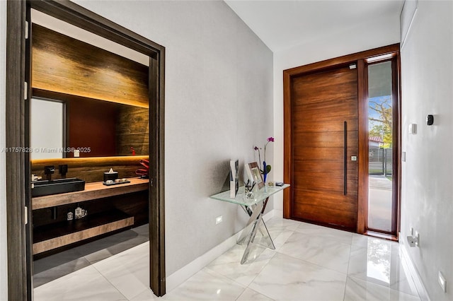 foyer with marble finish floor and baseboards