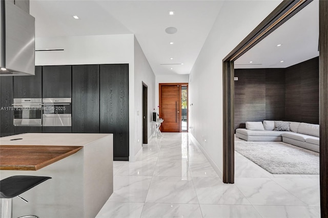 kitchen with baseboards, modern cabinets, dark cabinets, marble finish floor, and stainless steel oven