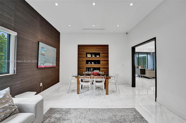 dining space featuring marble finish floor, an accent wall, and recessed lighting