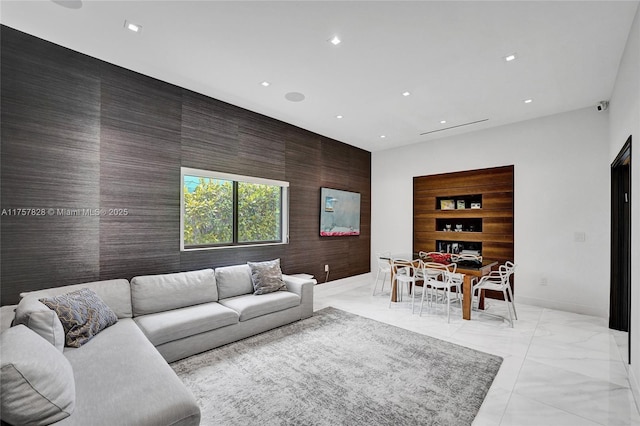 living area featuring an accent wall, recessed lighting, marble finish floor, and baseboards