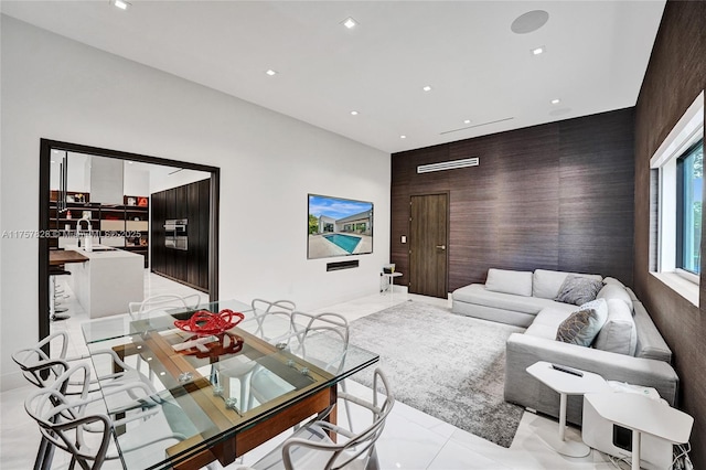 living area with an accent wall, recessed lighting, and marble finish floor