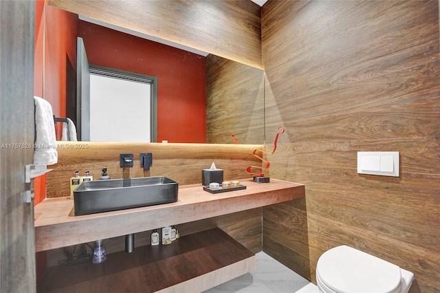 bathroom with marble finish floor, a sink, and toilet