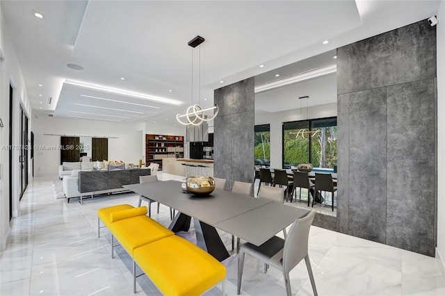 dining room featuring marble finish floor, an accent wall, and recessed lighting