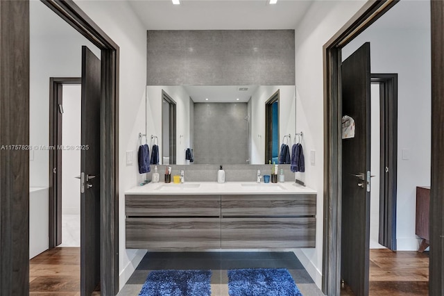 bathroom with wood finished floors, a sink, and double vanity