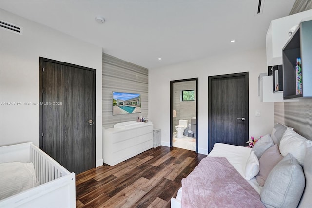 bedroom with recessed lighting, an accent wall, wood finished floors, visible vents, and baseboards